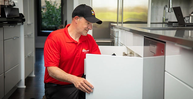 A technician inspecting an open drawer in a modern kitchen.