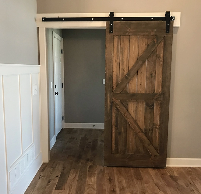 A rustic wooden sliding door hangs on a black track.