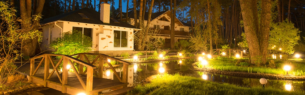 A serene nighttime scene featuring a cozy house surrounded by illuminated pathways.