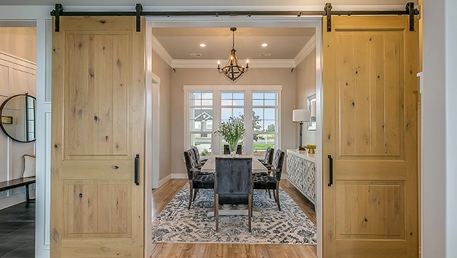 Open wooden barn doors into a stylish dining room.