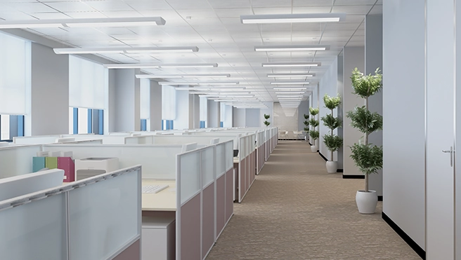Modern office interior featuring cubicles, large windows, and potted plants along a spacious corridor under bright overhead lighting.