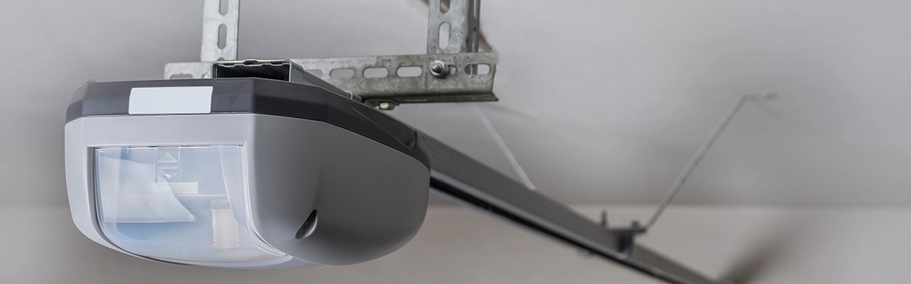 Close-up of a modern garage door opener mounted to the ceiling, featuring a sleek design and metallic support brackets.