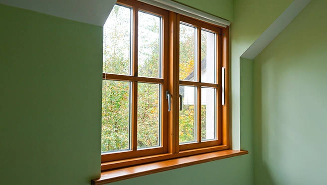 Bright wooden windows with a green wall.