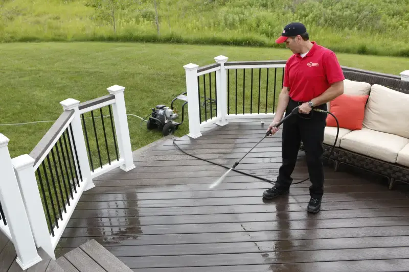 Handyman pressure washing a wooden deck.